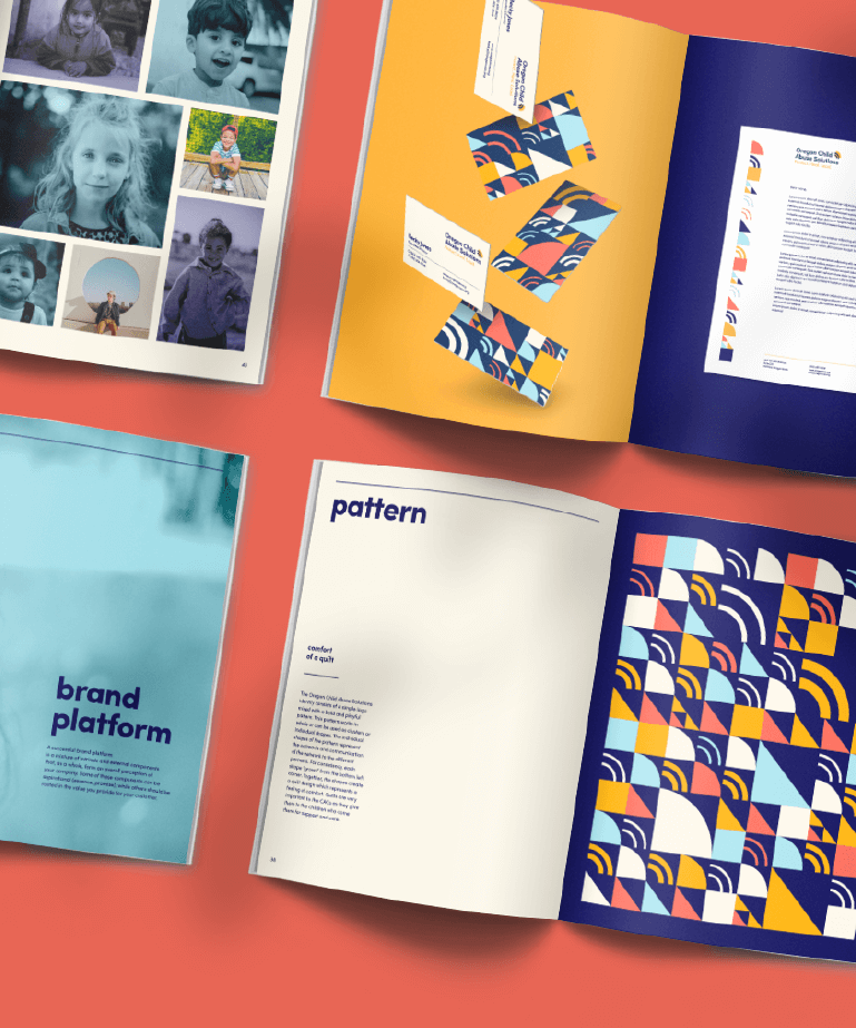 Four open books on a coral surface display colorful graphic design layouts, including photos of children, geometric patterns, the word “pattern,” and a page titled “brand platform.”.