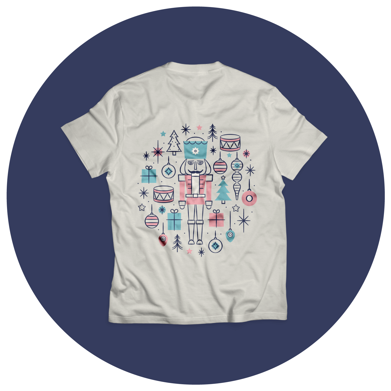 White T-shirt with a colorful graphic of a nutcracker surrounded by holiday icons like ornaments, drums, trees, stars, and snowflakes, in blue, pink, and black, displayed on a dark blue circular background.