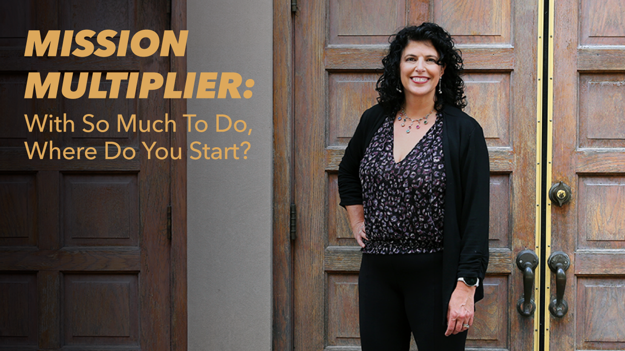 A smiling woman with curly dark hair stands in front of large wooden doors. Text reads: MISSION MULTIPLIER: With So Much To Do, Where Do You Start?.