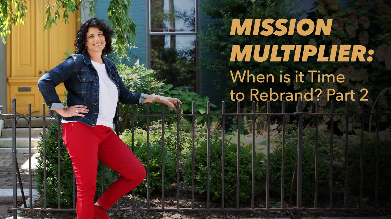 A woman with curly hair, wearing a denim jacket and red pants, stands by a black fence in front of a house. Text reads: Mission Multiplier: When is it Time to Rebrand? Part 2.
