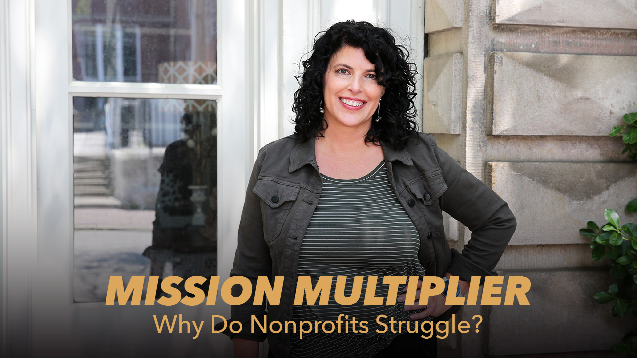 A woman with curly dark hair stands smiling outside a building, wearing a striped shirt and gray jacket. Text on the image reads: MISSION MULTIPLIER: Why Do Nonprofits Struggle?.