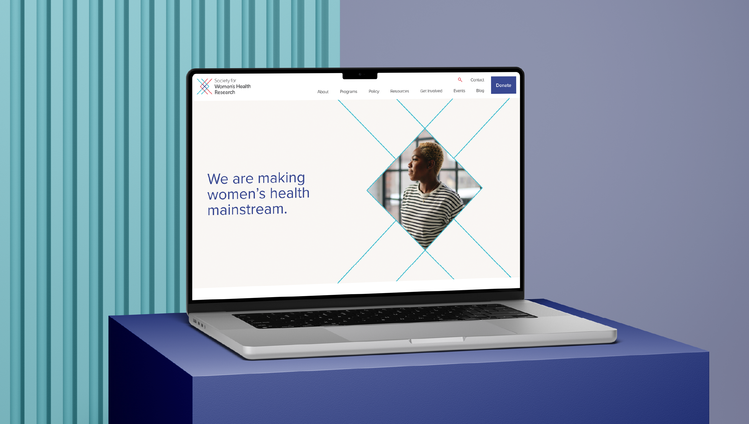 A laptop on a blue surface displays a website with the text We are making womens health mainstream and an image of a woman in profile, set against a background with vertical blue stripes.