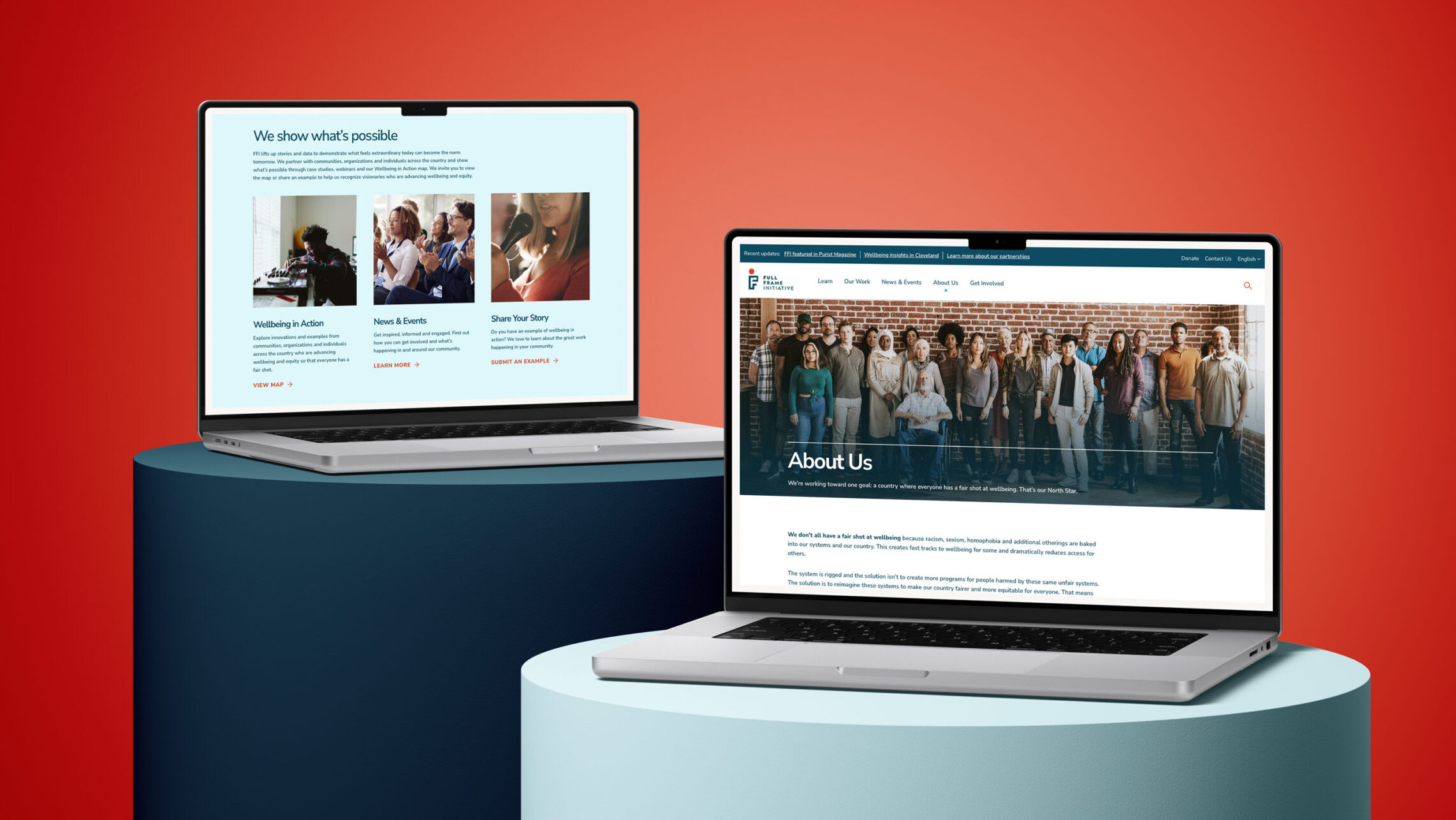 Two open laptops are displayed on cylindrical pedestals against a red background. The left laptop shows a page with articles and photos, while the right laptop displays an About Us page with a group photo of diverse people.