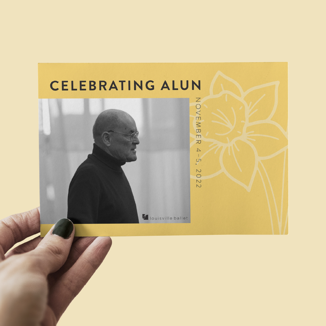 A hand holds a yellow postcard featuring a black-and-white profile photo of an older man in glasses and a turtleneck. The card reads Celebrating Alun and November 4–5, 2022 next to a line art flower illustration.