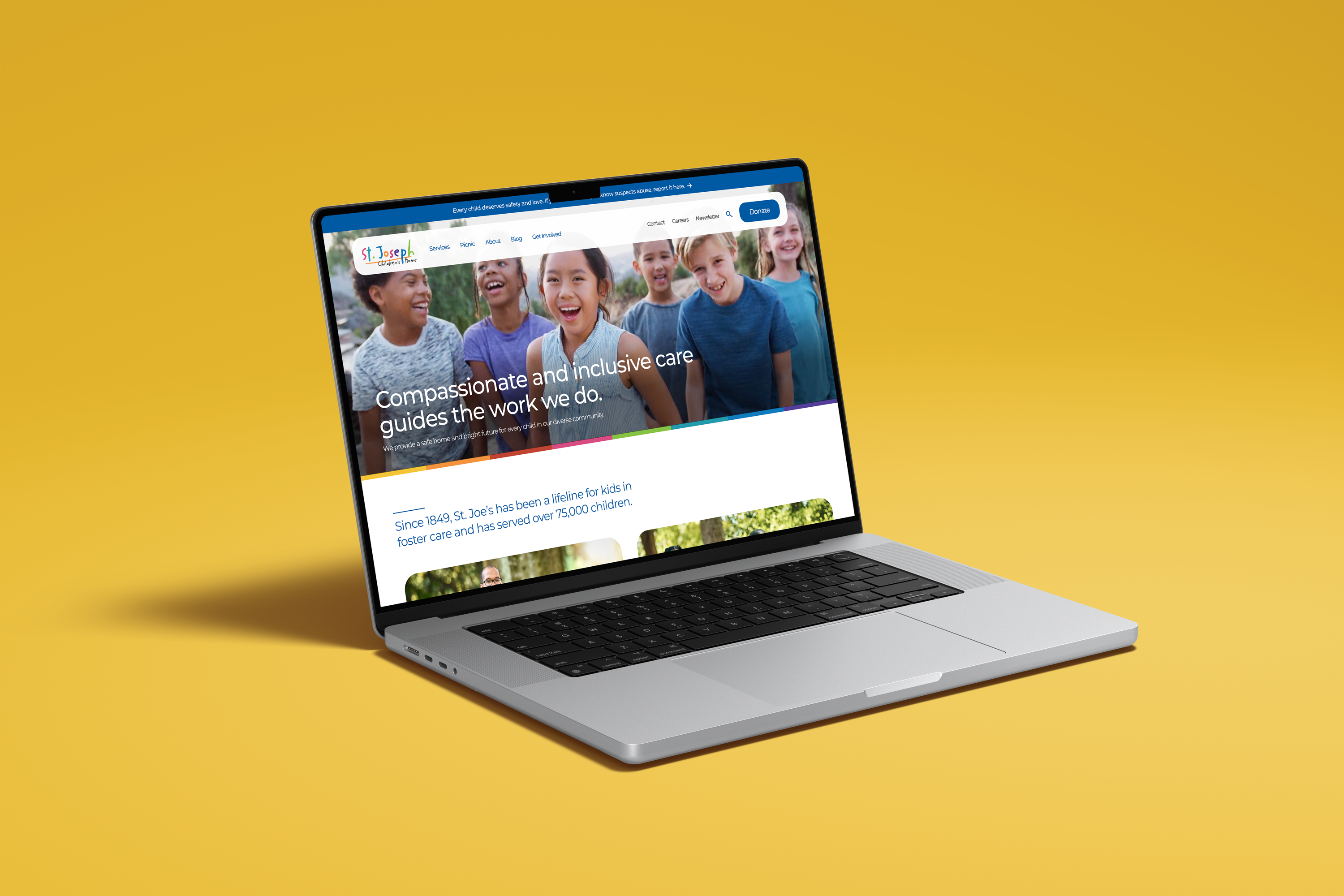 A laptop on a yellow surface displays a website with smiling children and text that reads, Compassionate and inclusive care guides the work we do. The site header features a colorful logo and navigation menu.